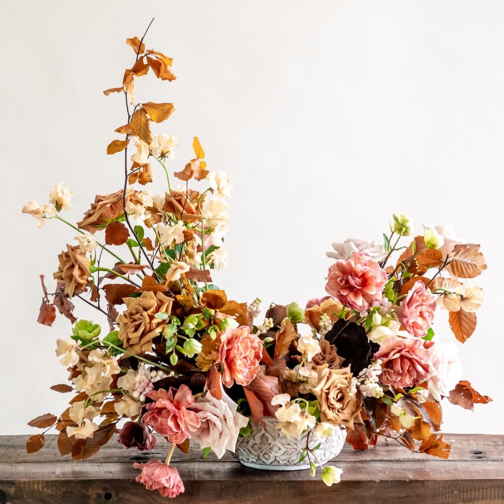 A c-shaped autumn arrangement in tones of toffee and pink by Maria Maxit