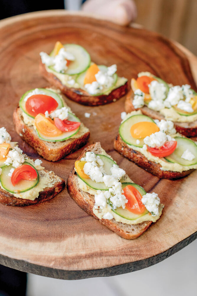 Pieces of toasts are served with cheese, cucumbers and tomatoes.