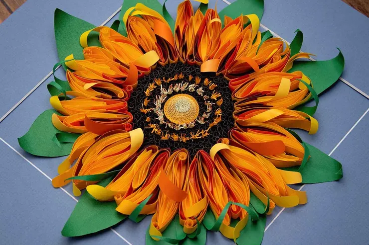 Strips of yellow, red, and orange paper create the illusion of a sunflower.