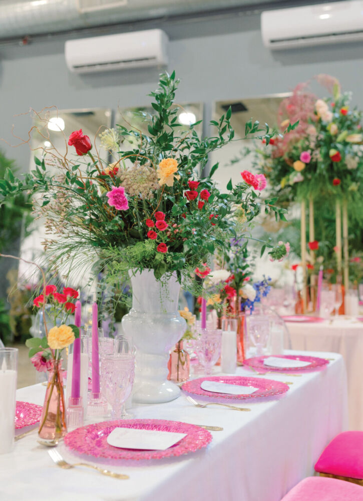 The pink table includes pink velvet chairs, pink plates, pink candles, and pink wildflowers.