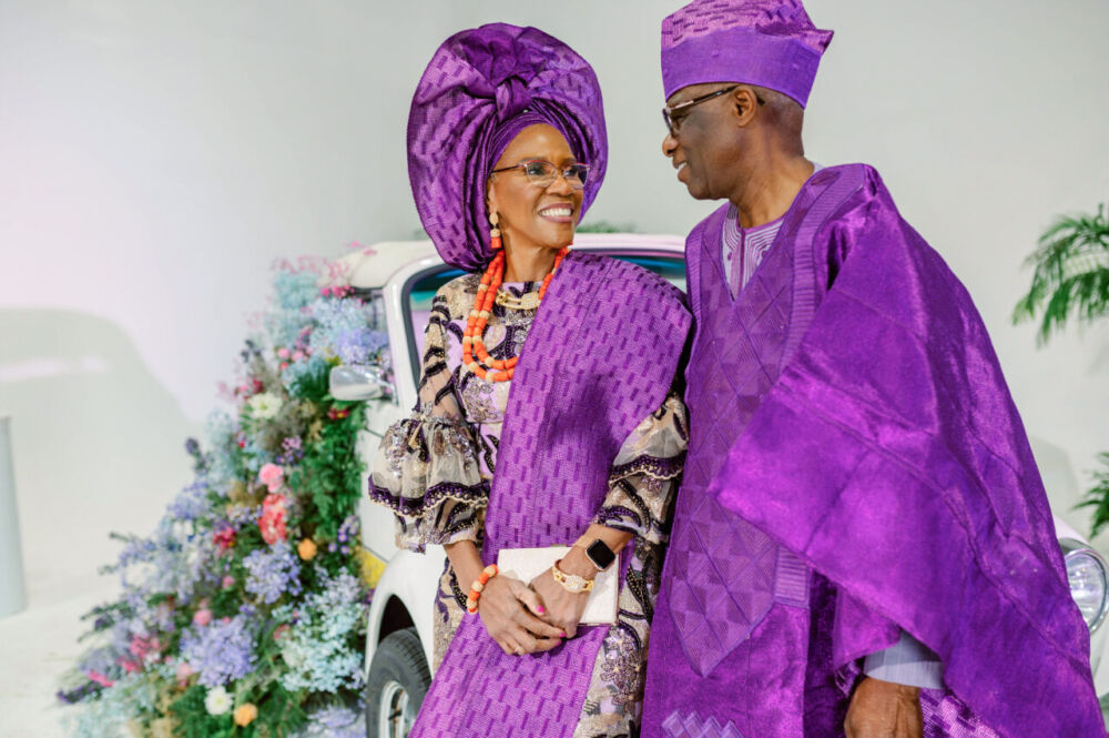 A married couple dressed in purple look lovingly into each other's eyes at her 70th birthday celebration.