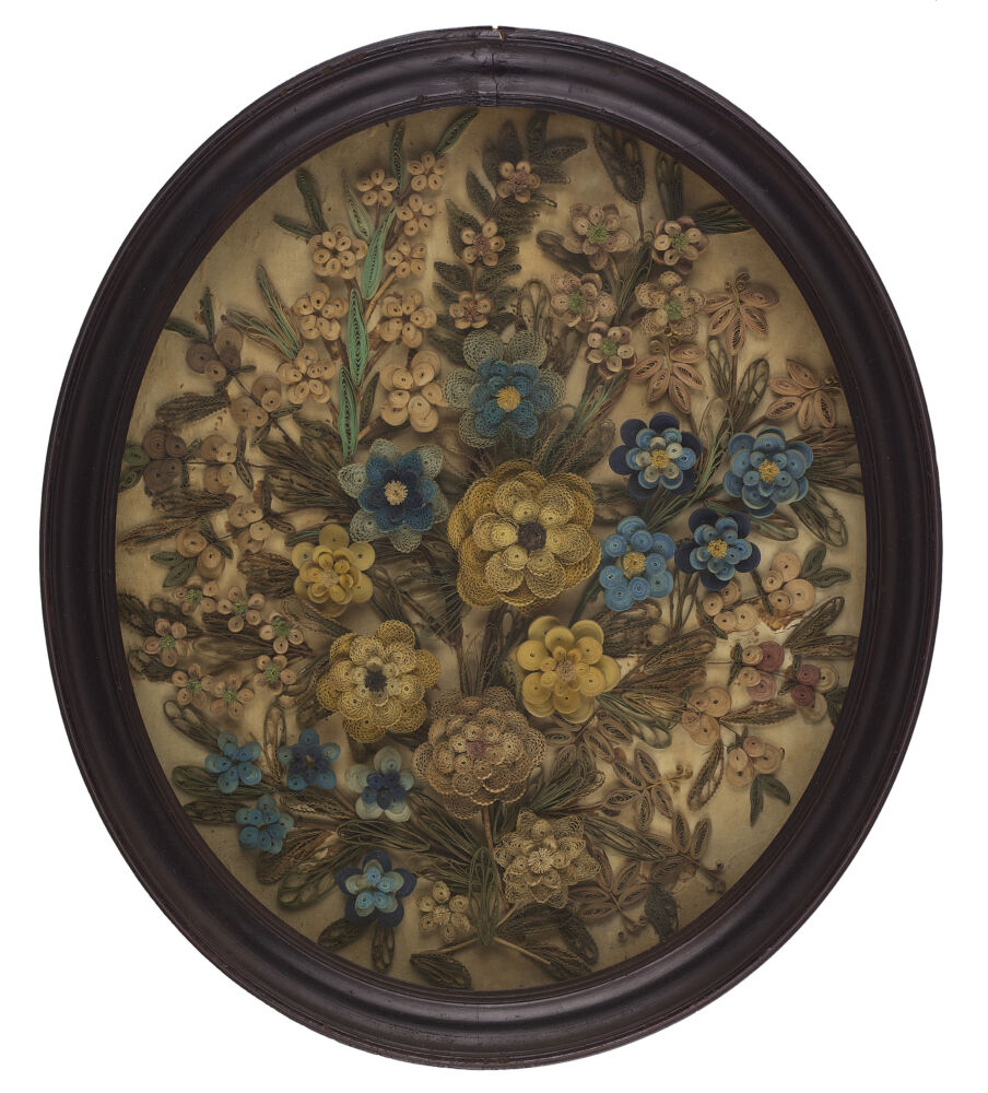 A faded quilling piece made up of yellow and blue flowers is contained in an oval frame.