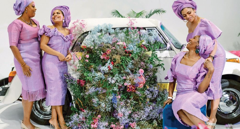 Four family members dressed in purple laugh together in front of a flowered car.