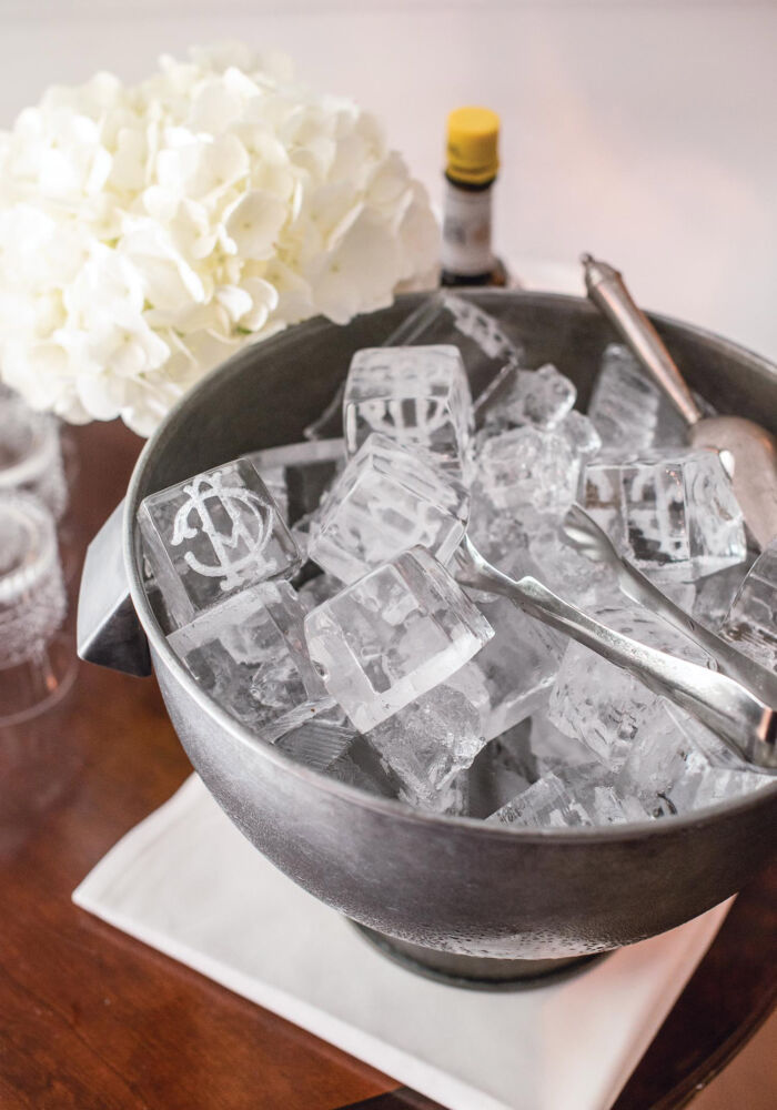 Ice cubes in a silver bowl have a printed monogram on them.