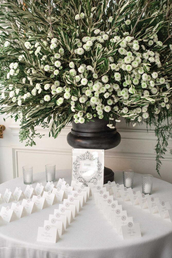 A large green and white button flower bouquet sits on a table with white name cards.