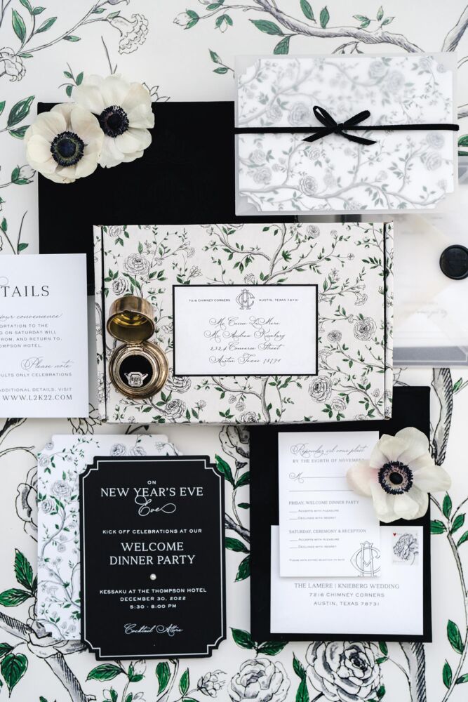 A black and white New Year's Eve wedding suite is displayed on a floral tablecloth.