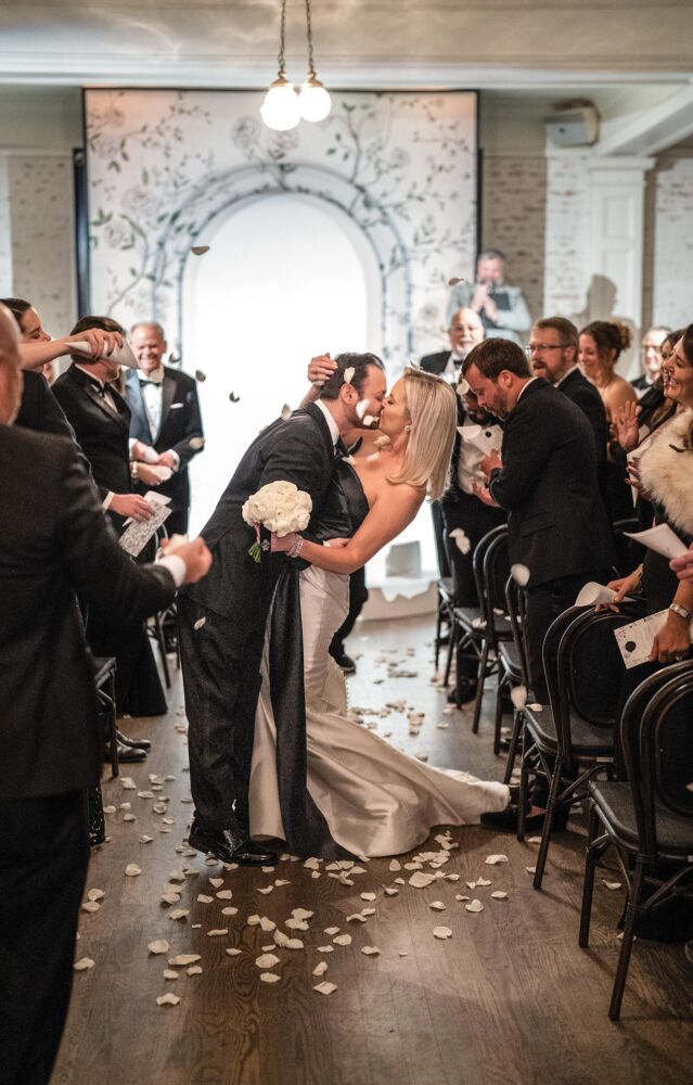 A bride and groom kiss on their way down the aisle at their New Year's Eve wedding.