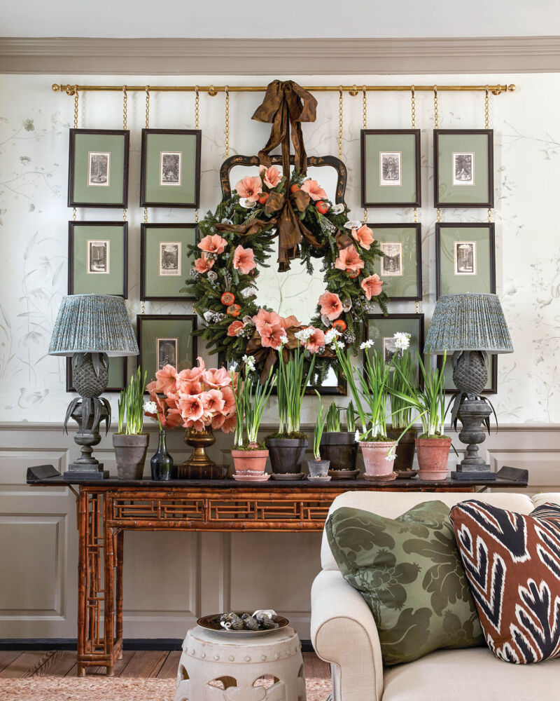 A pink floral wreath hangs above a bamboo console table.