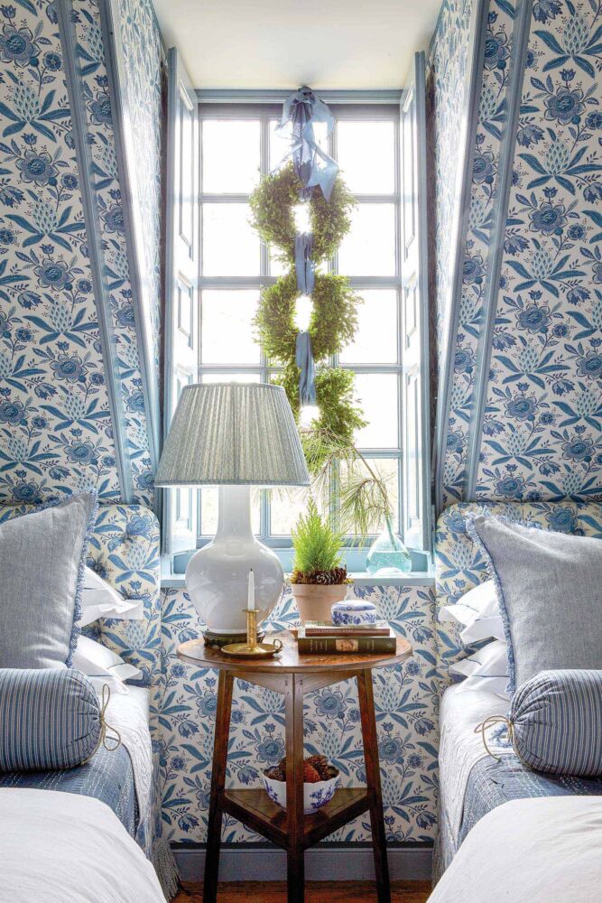 Three wreaths hang in a bedroom with blue floral wallpaper.