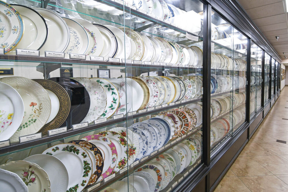 Hundreds of porcelain plates are on display behind a glass case.