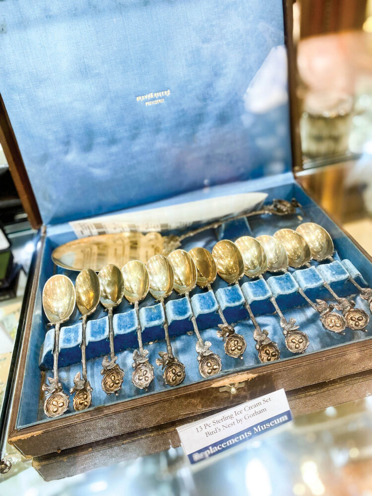 A dozen gleaming spoons are kept inside a blue velvet box.