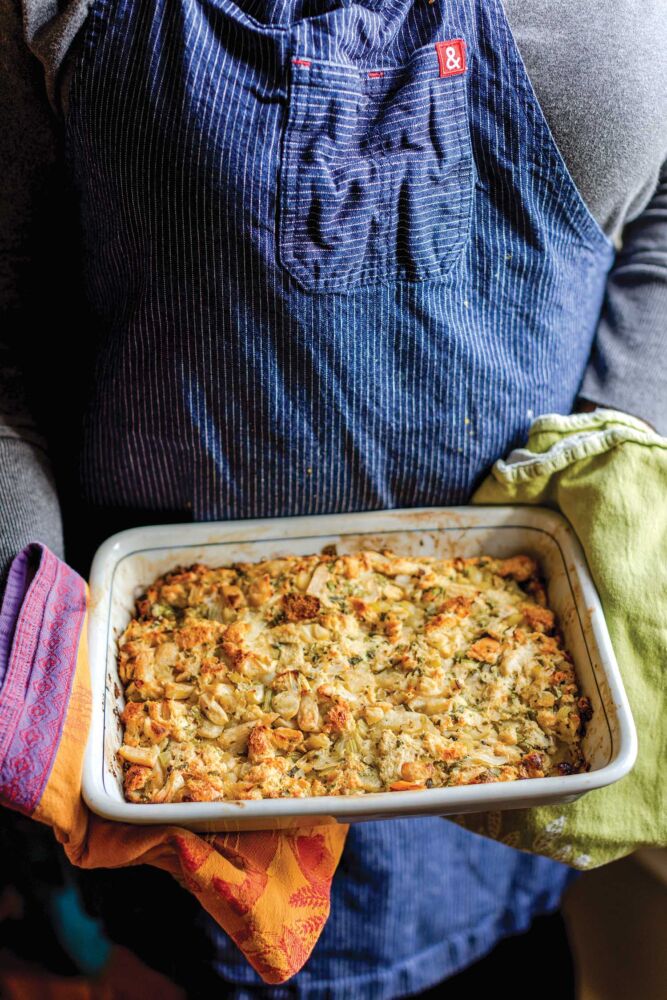 Hands with towels holding casserole dish of cornbread dressing.