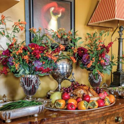 A wooden hutch holds fruits and flowers nexts to red striped lamps.