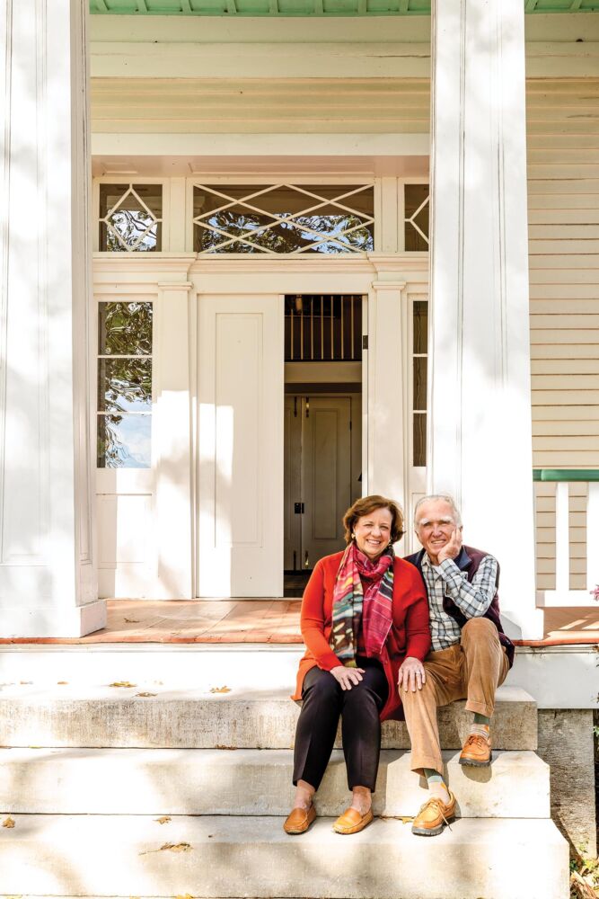 A husband and wife sit on the front steps of their porch.