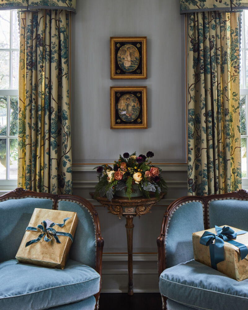Two presents wrapped with a silky cobalt bow rest on two velvet chairs.