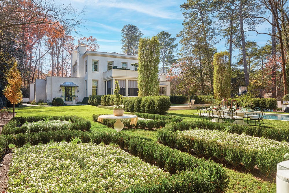 Lush green hedges cover the grounds outside a white regency style home.