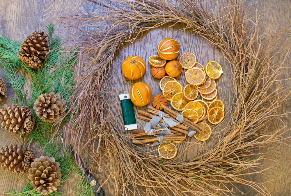Oranges and pine cones lay next to a twig wreath.