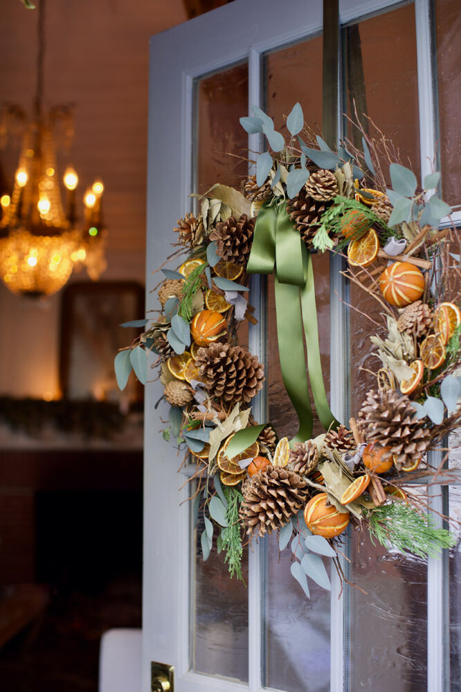 A dried citrus wreath hangs on a french blue door.