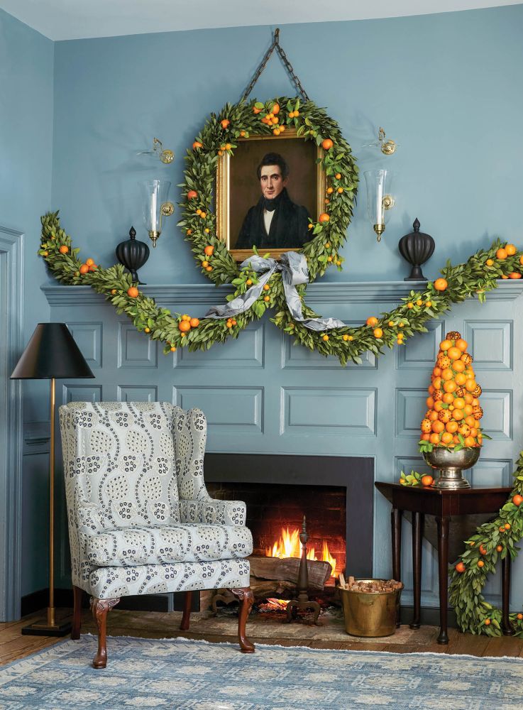 A blue mantel is decorated with greenery and oranges.