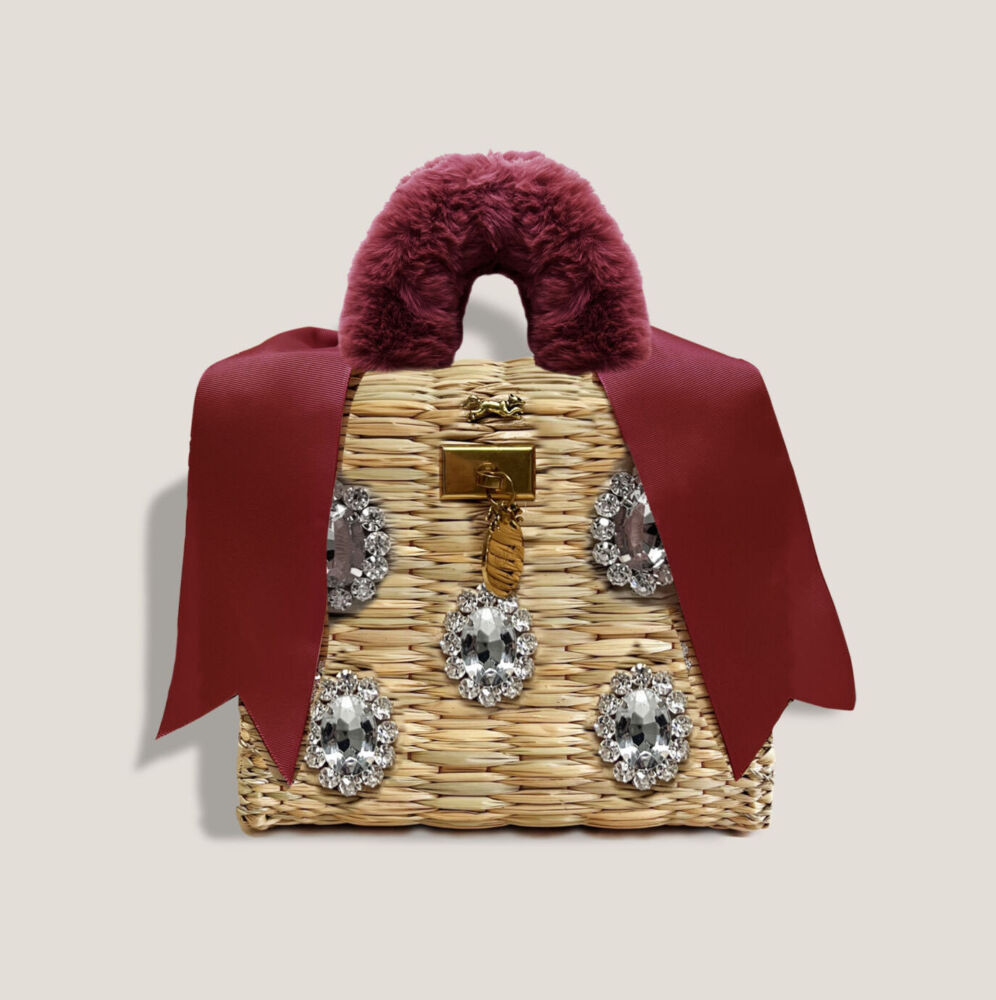 A mini woven bag has encrusted jewels and a fur handle with ribbons.