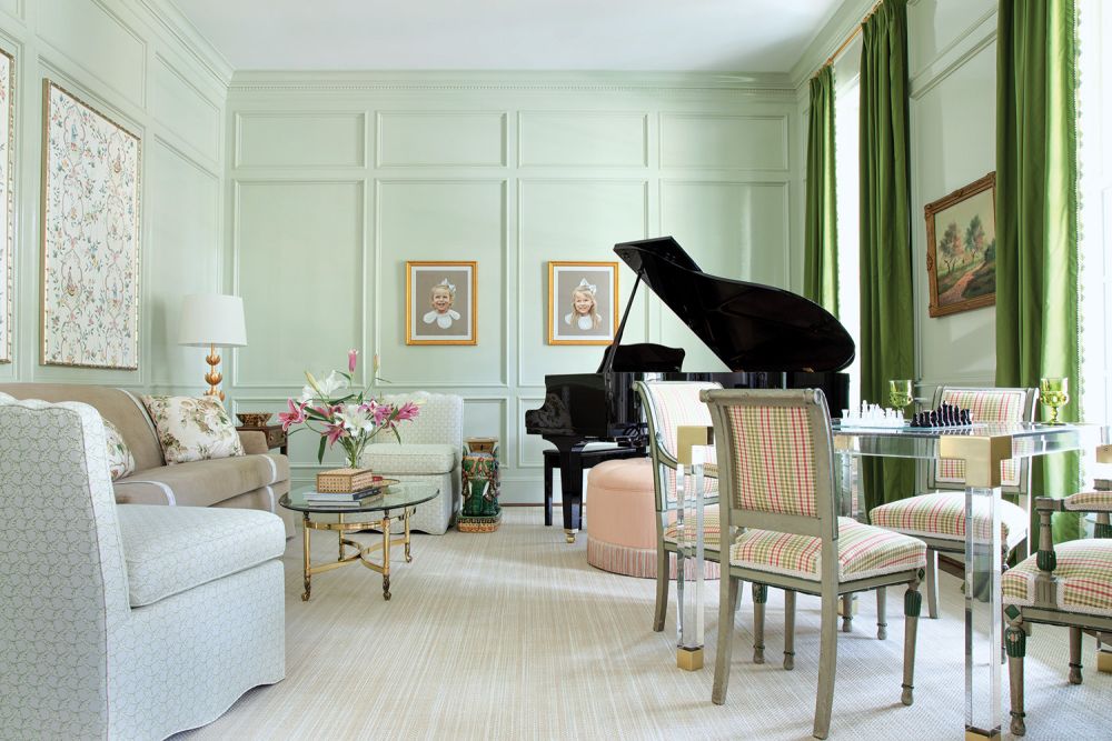 Pale green walls encase a music room with a large black grand piano.