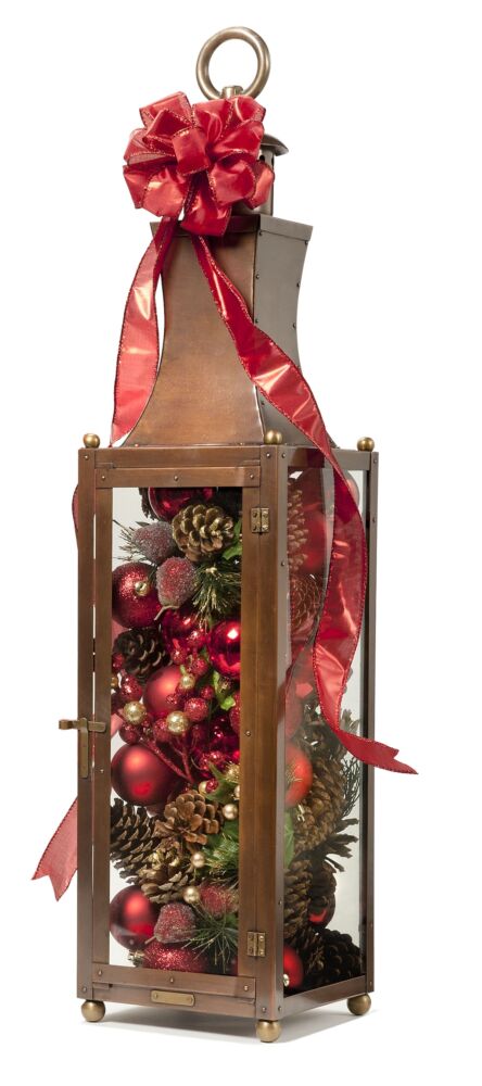 Bevolo candle lantern decorated with red ribbon and Christmas ornaments.