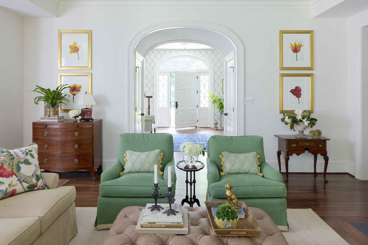 Green chairs sit in a white living room decorated with other antiques.