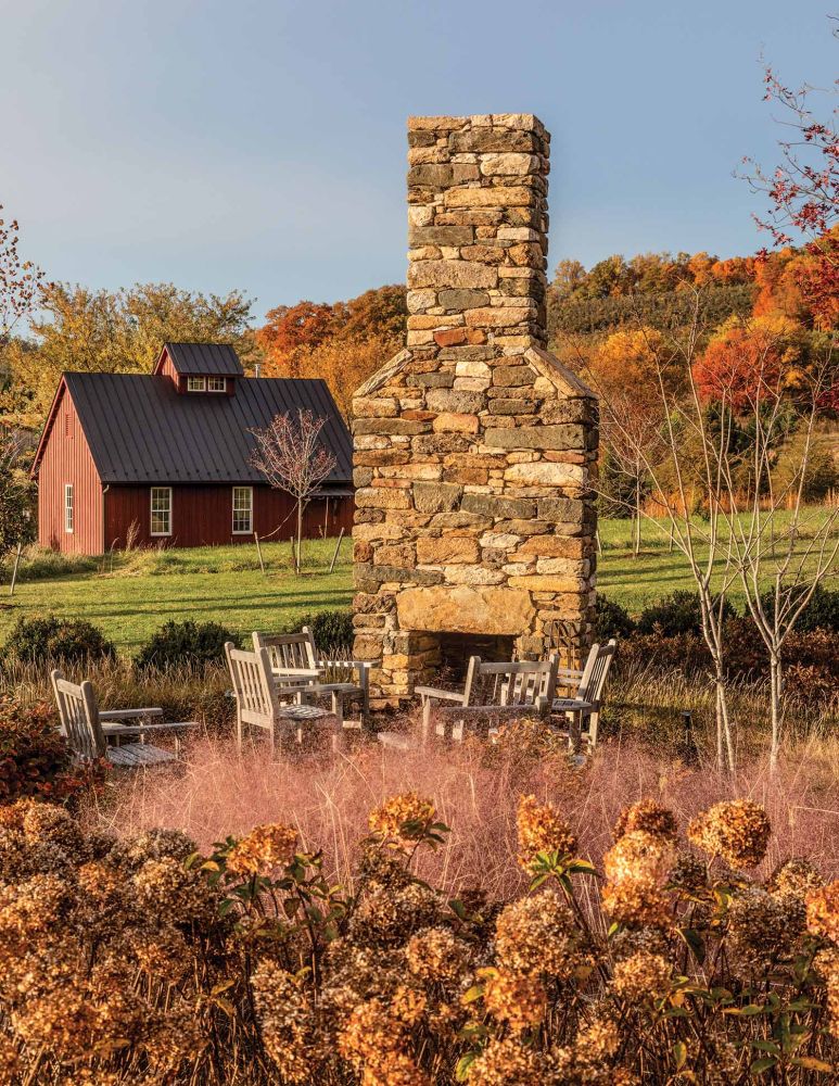 A stone fireplace sits behind dried brown hydrangeas.