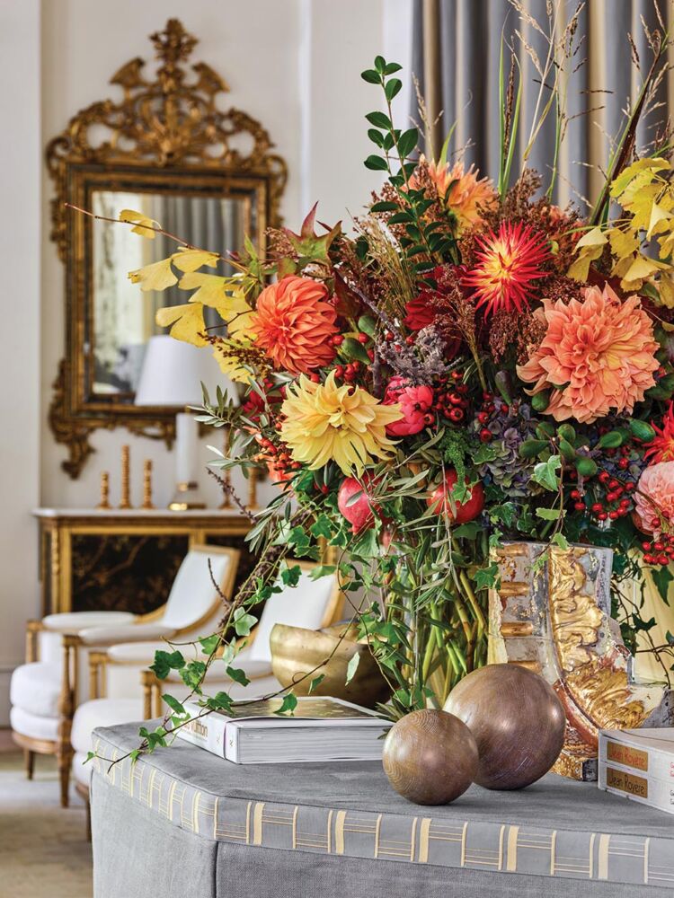 An arrangement of dahlias and peonies with green hydrangea blossoms, golden ginkgo and red sweetgum foliage, tendrils of ivy, spiky and cascading grasses, and bare branches.