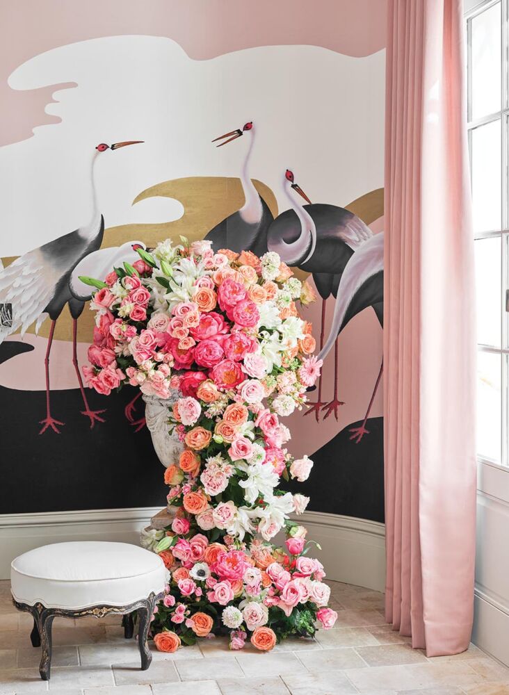 A waterfall of pink and orange roses cascades out of an urn.