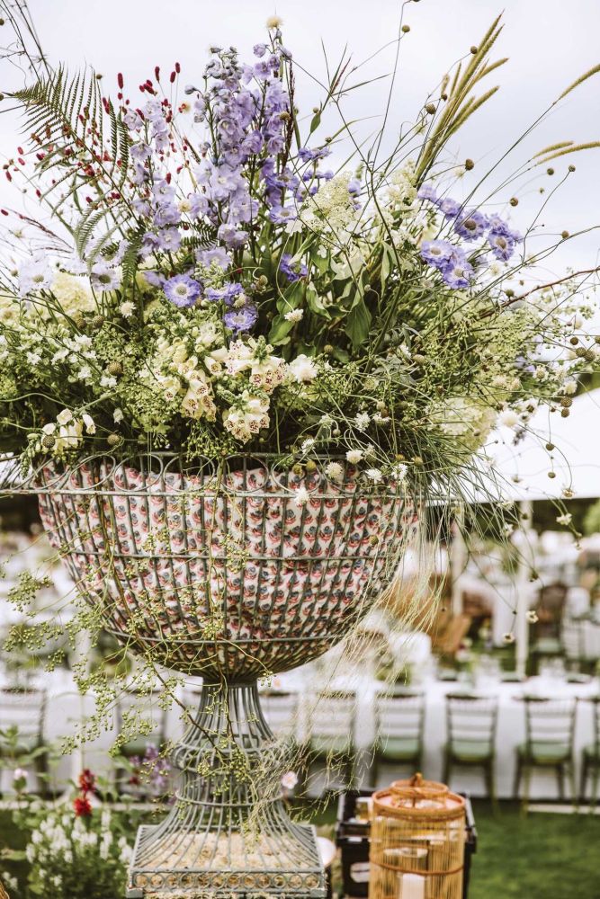 Scabious, foxgloves, delphinium, and Sanguisorba in a wire urn lined with block-printed fabric.