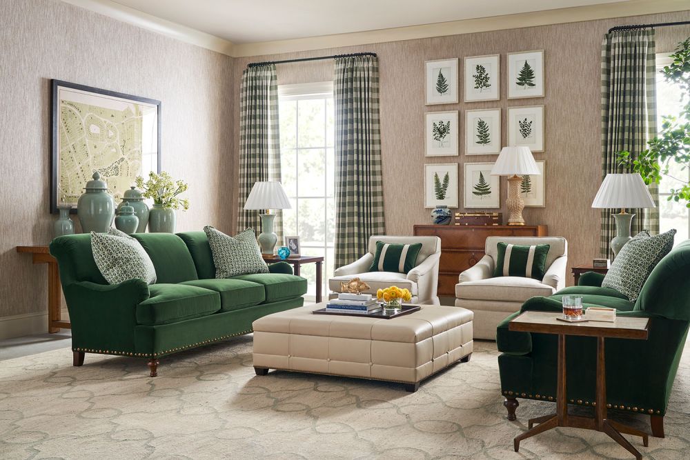 Two green sofas, beige chairs, and a quilted ottoman in a beige living room.