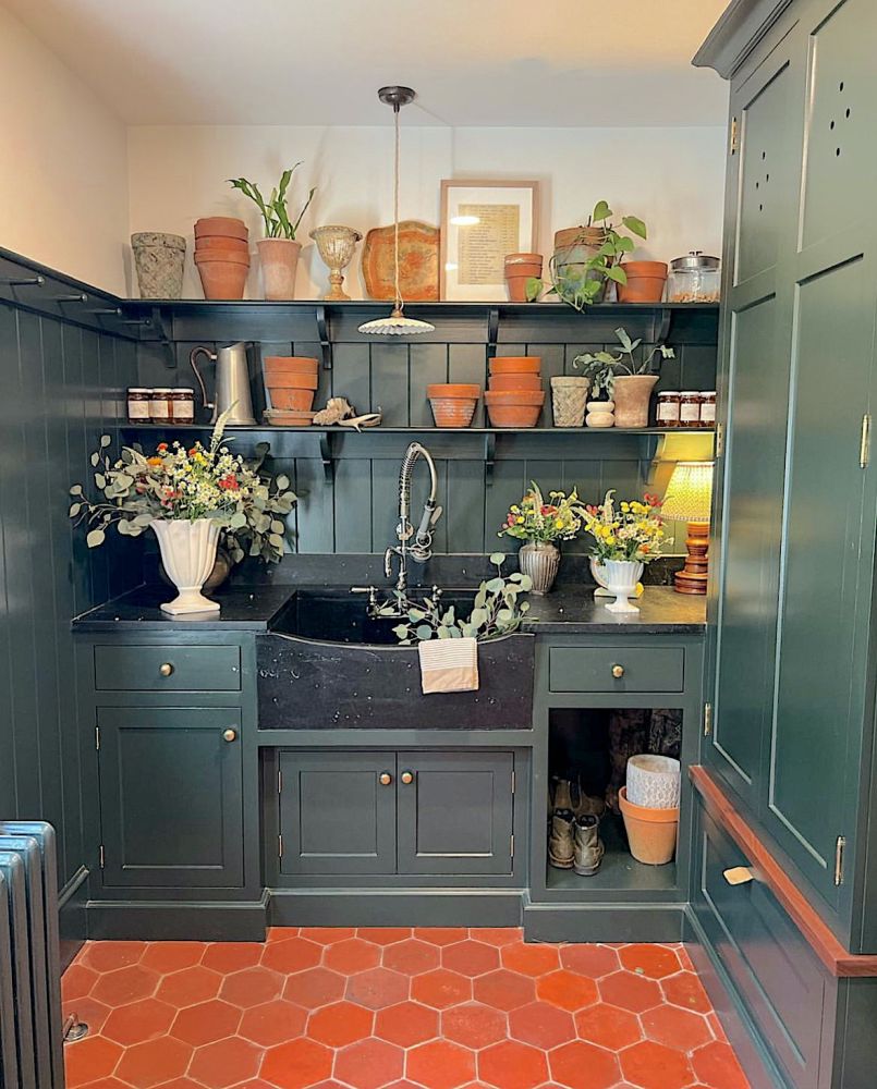 Flower arranging room with dark green painted cabinets and shelves with black soapstone sink.
