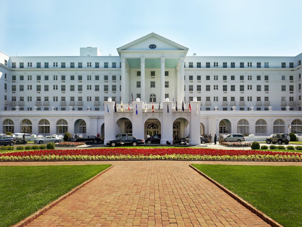 Exterior of The Greenbrier Resort with lawn and bed of tulips in front of the entrance.