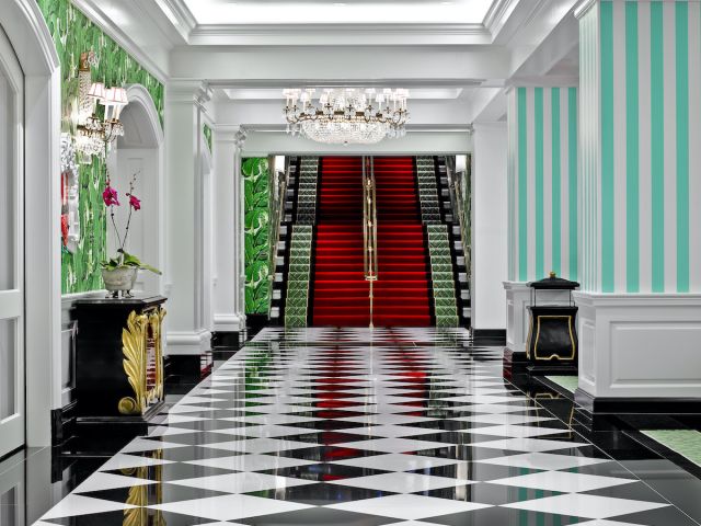 The Greenbrier Avenue staircase carpeted in red and green with black borders. Black and white tiled floor foreground.