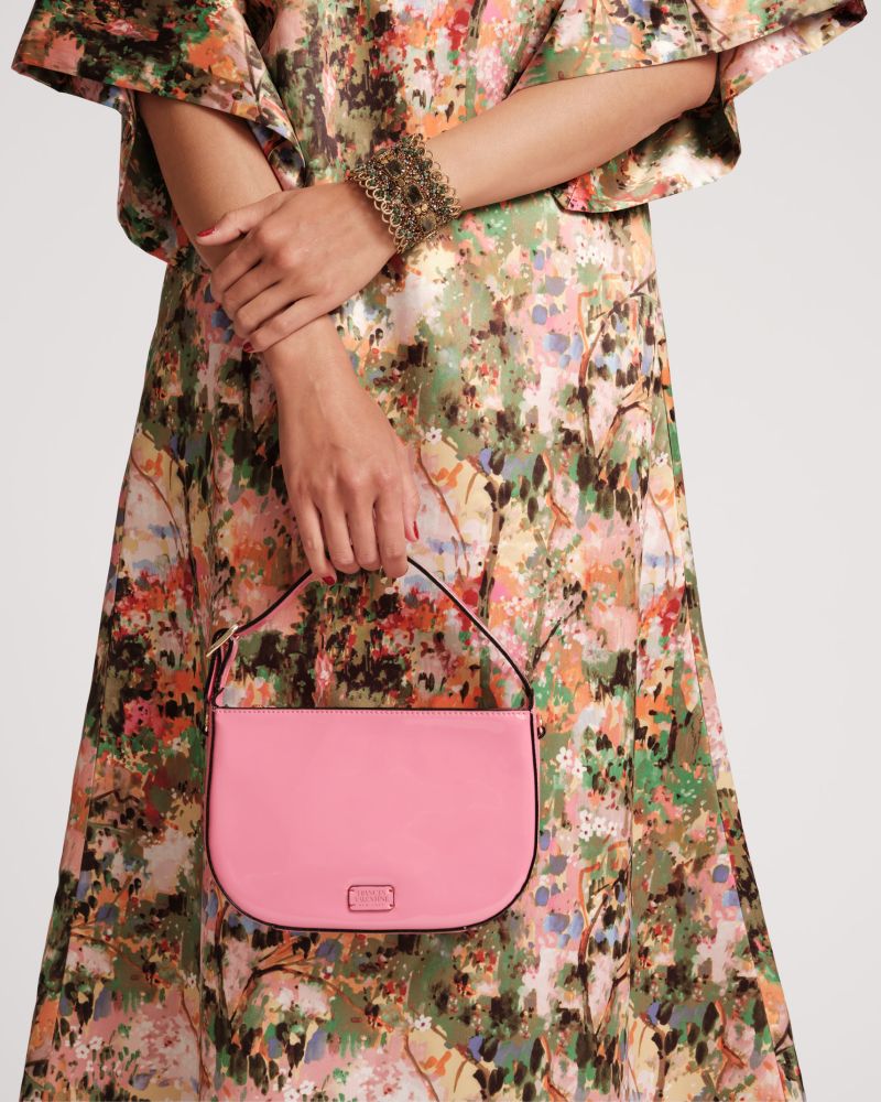Woman in printed dress holding a pink bag.