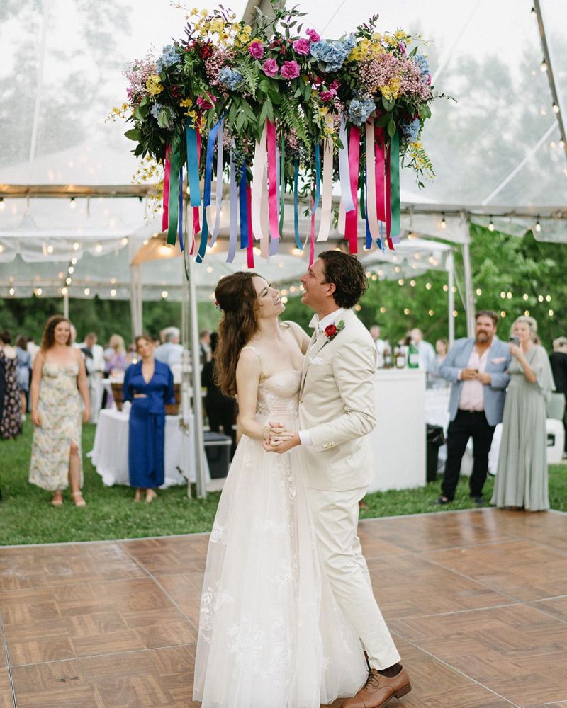 Ribbons hang from a floral arrangement above a bride and groom.