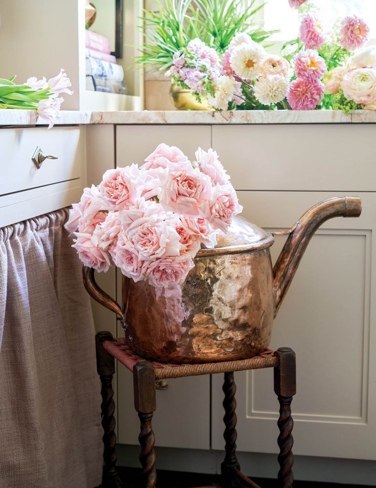 Fluffy pink roses are in a copper watering tin.