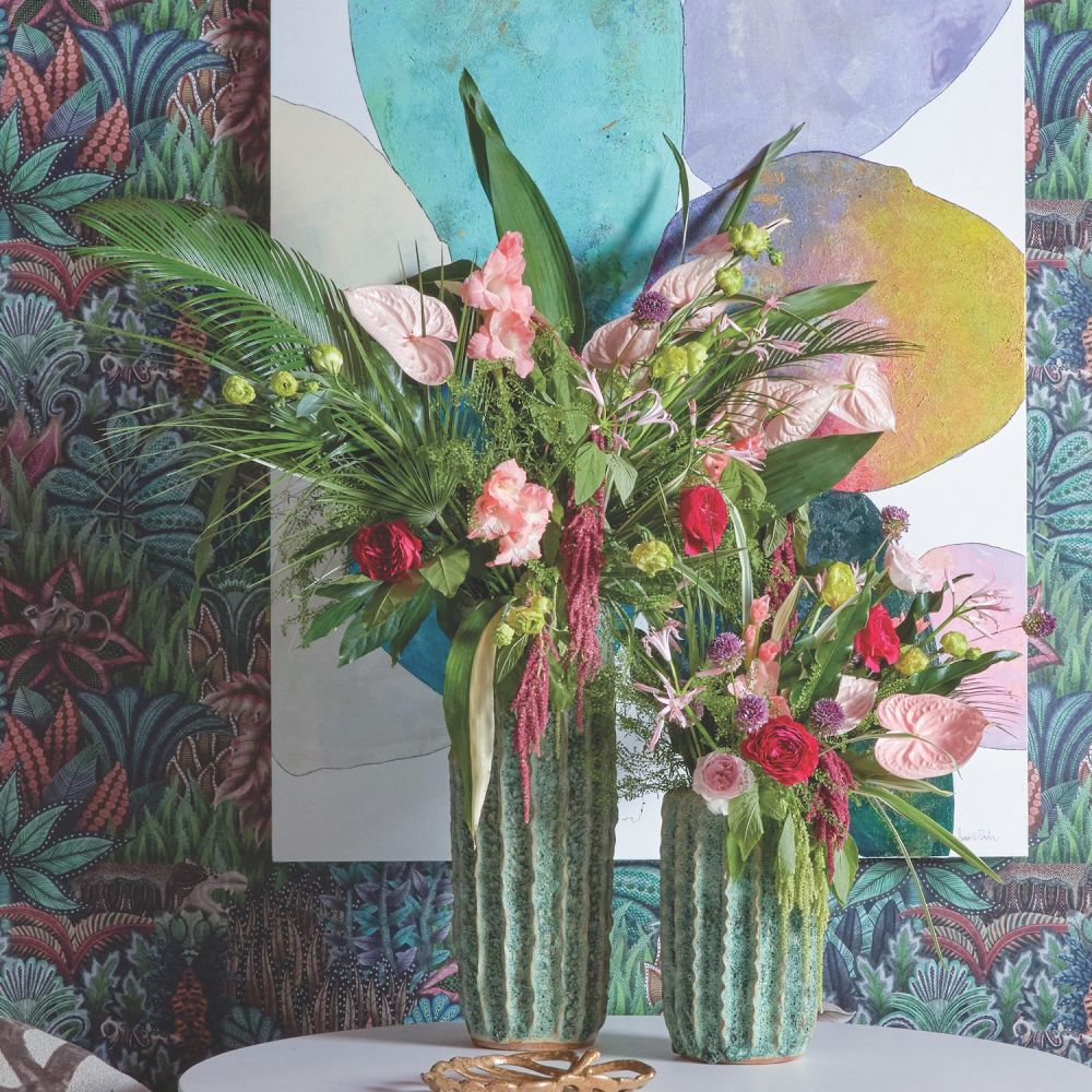 A pair of tropical-inspired arrangements on a round white table in the Flower Showhouse media room