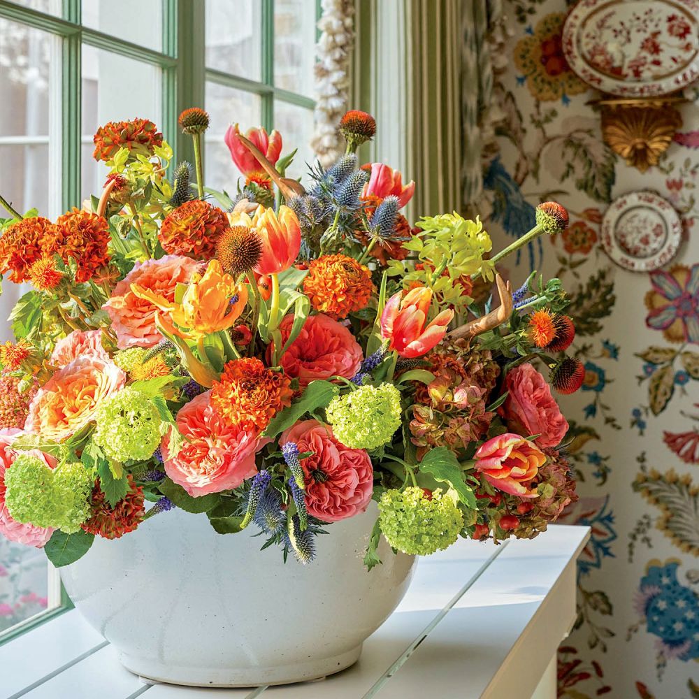 A symphony of peach roses, coral tulips, amber pon pon ranunculus, snowball hydrangeas, lilacs, sea holly, and echinacea cone flowers.