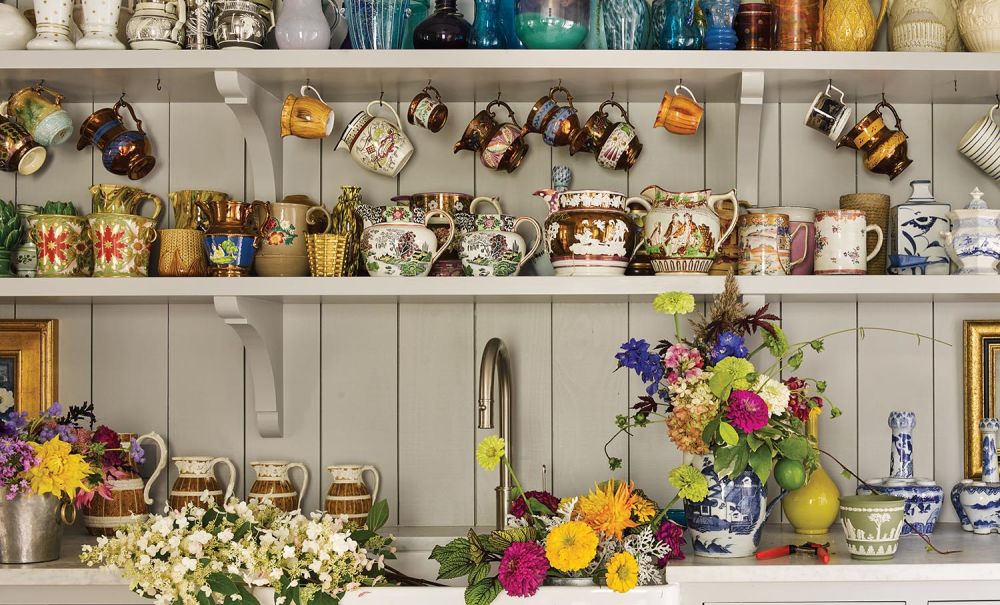 A flower room has flowers in the sink, blue and white containers, and mugs on the shelf.
