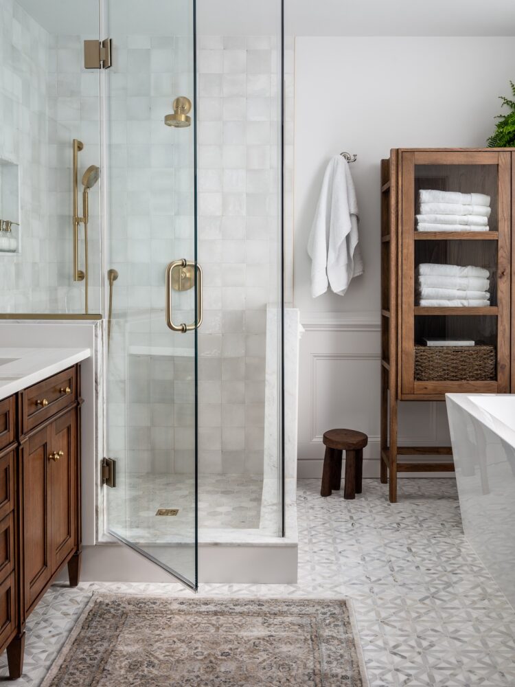 A narrow glass front cabinet to store towels and other items in a bathroom.