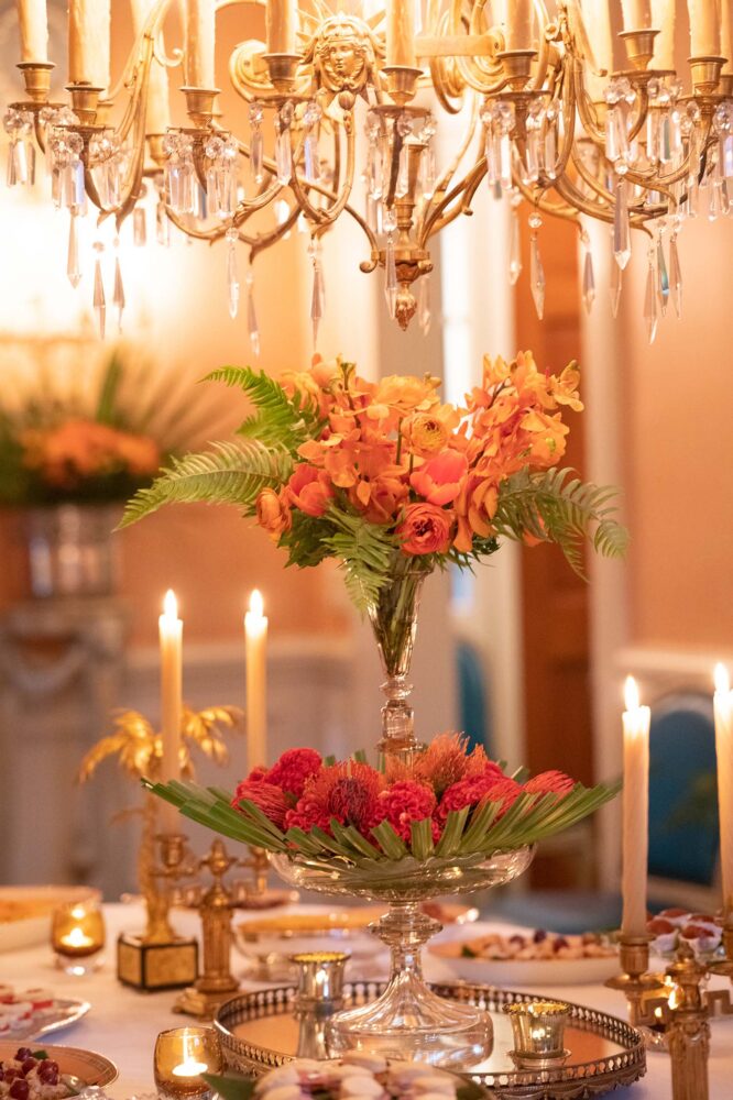 A trumpet of orange flowers decorate a table.
