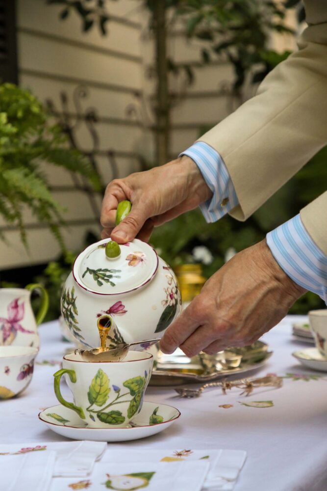 Hands pouring tea out of a teapot.