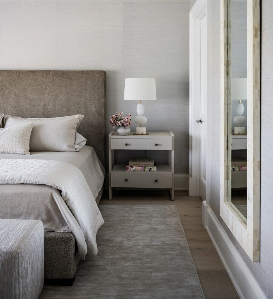 Bedroom in a soothing gray and white palette. The bedside table blends right in with the setting and provides both open storage and drawers.