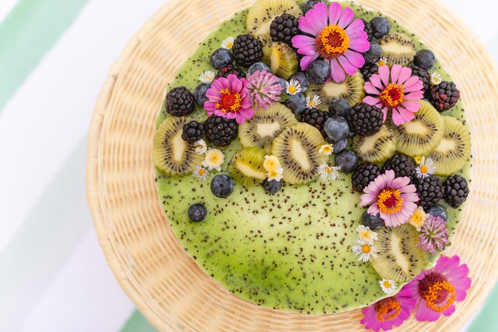A kiwi cheesecake has a green top with flowers and berries.