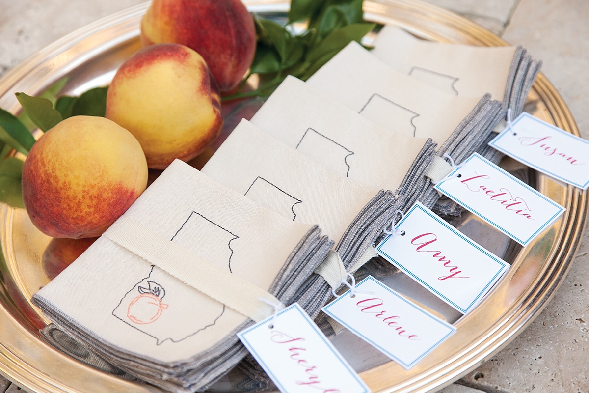 Peaches on a silver platter next to napkins and name tags.
