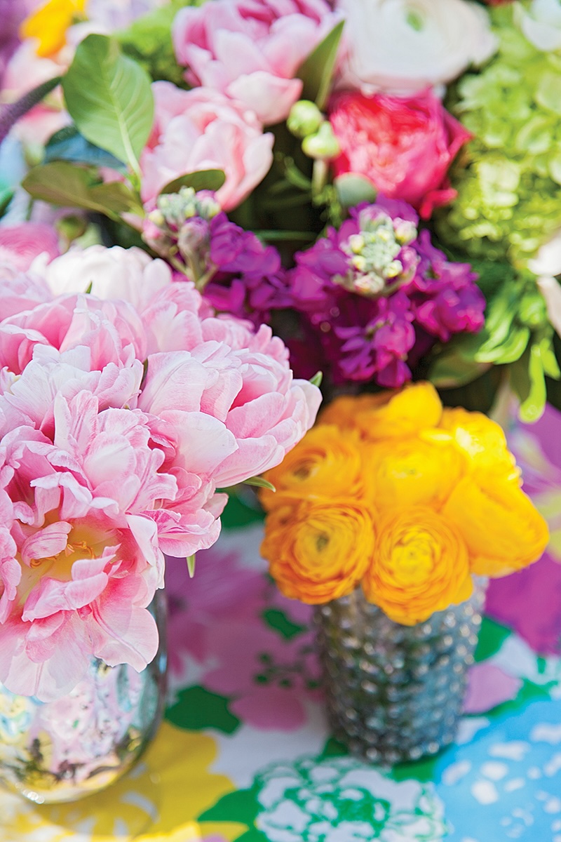 A bouquet of peonies and a bouquet of ranunculus on a colorful table.