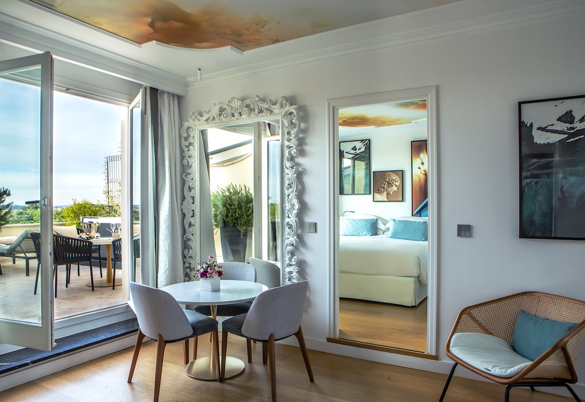 Suite at Sofitel Rome Villa Borghese, bed reflected in mirror, open doors onto terrace.