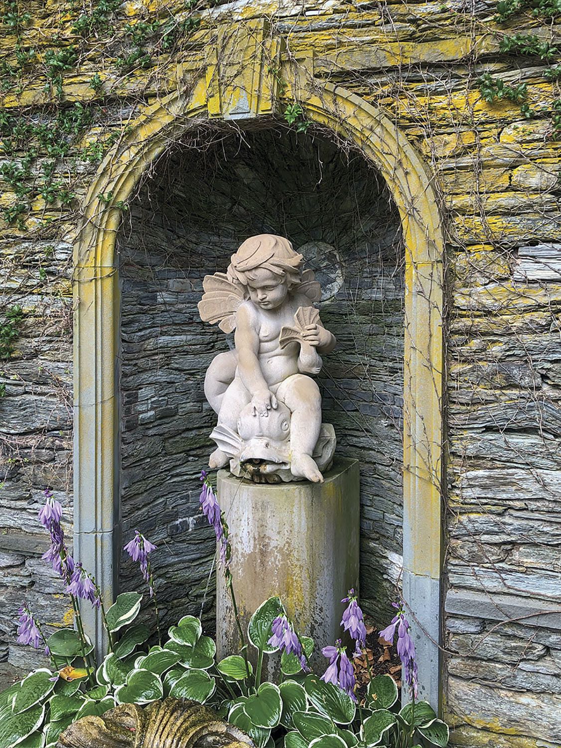 A fountain features Cupid astride a dolphin in an elegant niche in the East Garden